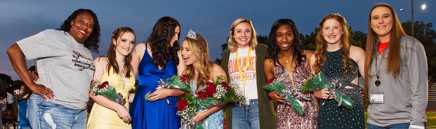 Volleyball players on the homecoming court gather with their coaches.